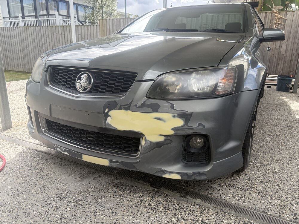 Damaged Holden Commodore front bumper before mobile paint repair in Brisbane