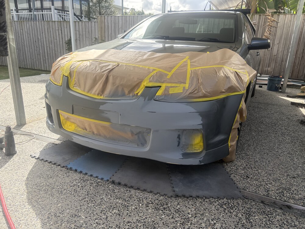Holden front bumper masked and in grey primer during mobile paint repair in Brisbane